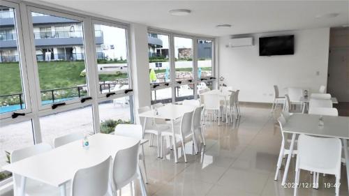 a restaurant with white tables and chairs and windows at Departamento Veneto Village - B in Villa Parque Siquiman