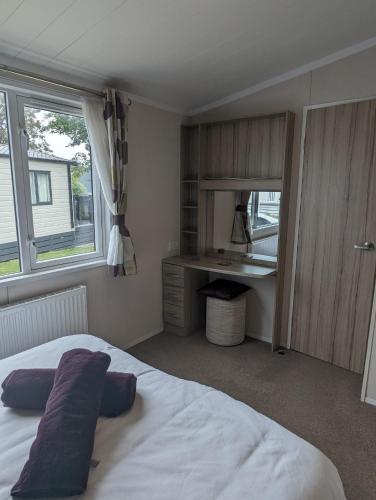 1 dormitorio con cama, escritorio y ventana en BEAUTIFUL LODGE on SHOREFIELD Country Park on edge of New Forest ENTERTAINMENT AND LEISURE PASSES INCLUDED, en Milford on Sea