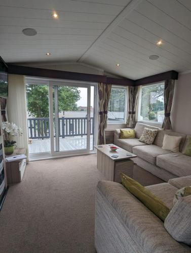 a living room with a couch and a table at BEAUTIFUL LODGE on SHOREFIELD Country Park on edge of New Forest ENTERTAINMENT AND LEISURE PASSES INCLUDED in Milford on Sea