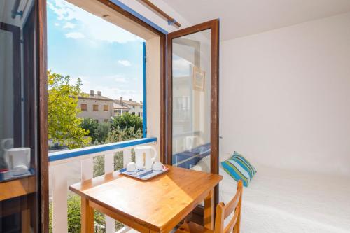 a balcony with a wooden table and a window at Studi-Hôtel Résidence Plein Voile in Les Salles-sur-Verdon