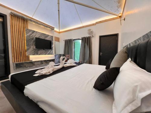 a bedroom with a large bed with towels on it at The Whispering Palms Resort in Bhopal