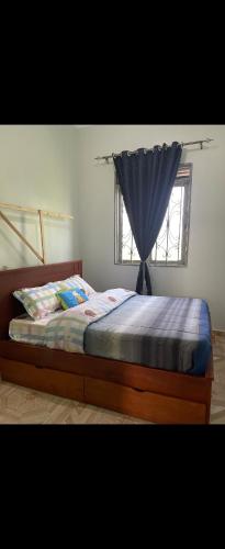 a bed with a blue comforter and a window at Muhabura view imfizi farmhouse in Kisoro