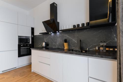 a kitchen with white cabinets and black counter tops at Luxury Apartments Laborca in Uzhhorod