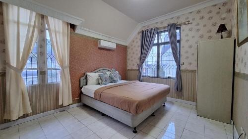 a bedroom with a bed and two windows at Villa Kota Bunga By akuvilla in Puncak