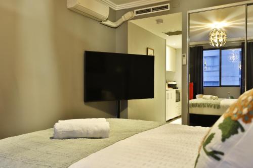 a bedroom with two beds and a flat screen tv at Vintage Charm Oasis - CBD Living with Parking in Sydney