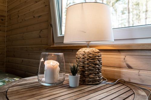 a table with a lamp and a candle on it at Kempings Bejas in Babīte