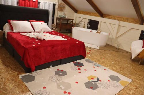 a bedroom with a bed with a red blanket and a tub at La Petite Maison de Marie in Sainte-Marie