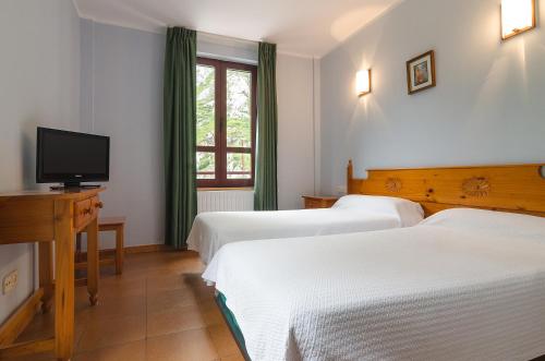um quarto de hotel com três camas e uma televisão em Arcea Mirador de Cabrales em Poncebos