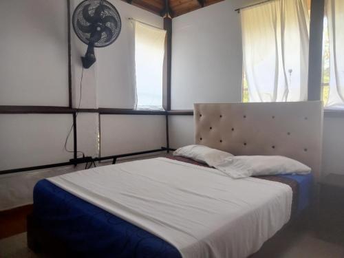 a bedroom with a bed with a white blanket and two windows at HOSPEDAJE TURÍSTICO CAMPESTRE "VILLA ALONDRA" Parqueo Privado! in Villavicencio
