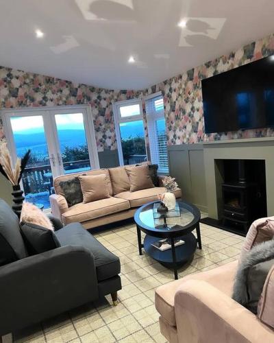 uma sala de estar com sofás, uma mesa e uma televisão em Luxury Lodge With Hot Tub In Royal Deeside em Strachan