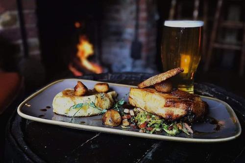 a plate of food with meat and potatoes and a glass of beer at The Black Horse Inn in Maidstone