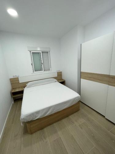 a white bedroom with a bed and a window at Habitación en Planta Baja con terraza in Barcelona