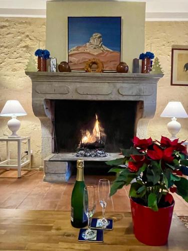 a living room with a fireplace with a bottle and two wine glasses at Gîte de La Peloue - Jolie Maison dans les vignes in Barsac