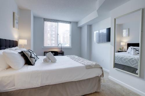 a bedroom with a large white bed and a mirror at Apartment Just Steps from Ballston Subway Station in Arlington