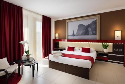 a bedroom with a large bed with red curtains at Kairos Garda Hotel in Castelnuovo del Garda