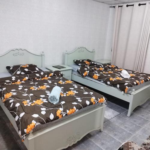 two twin beds in a bedroom with flowers at العين الهيلي مصباح ب 2 in Al Ain
