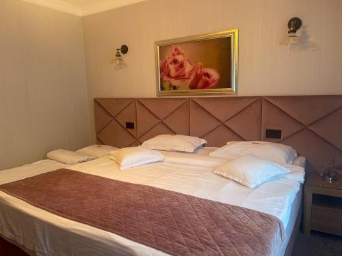 a bedroom with a large bed with white sheets and pillows at Hotel Roser House Boutique - pe malul lacului Colibita in Colibiţa