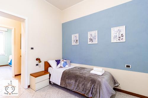 1 dormitorio con cama y pared azul en FamilyBO Apartments Murri - Self Check-in, en Bolonia