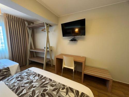 a room with a bed and a desk and a television at Hotel El Tambo 2 in Lima