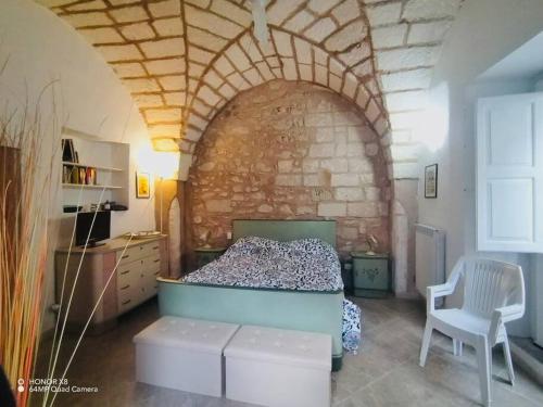 ein Schlafzimmer mit einem Bett und einer Ziegelwand in der Unterkunft La casa del pellegrino in Carpignano Salentino