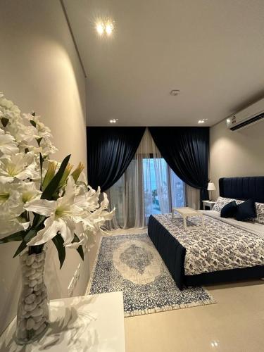 een slaapkamer met een bed en een vaas met witte bloemen bij Sifah Ocean Breeze Villa in Muscat