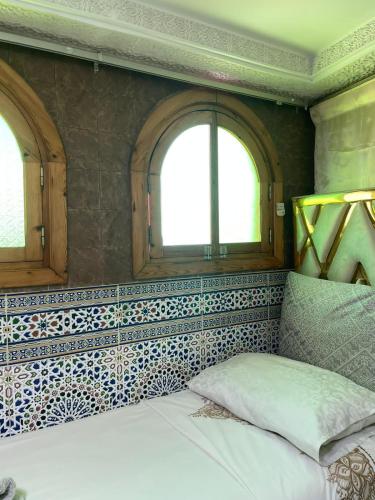 a bedroom with two windows and a bed in it at Riad Malak in Meknès