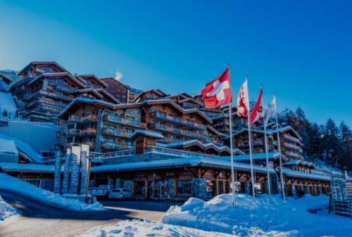 a lodge in the snow with flags in front of it at Superbe appartement au centre de la station in Nendaz
