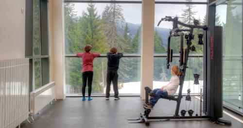 three people looking out the window of a gym at Euphoria Club Hotel in Borovets