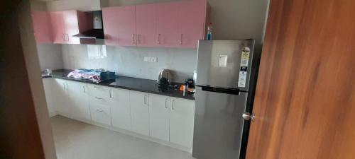 a kitchen with pink cabinets and a stainless steel refrigerator at Nanma East Fort in Mūvattupula