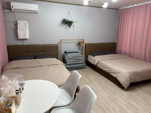 two beds in a room with a table and chairs at Sacheon Songlim in Gangneung