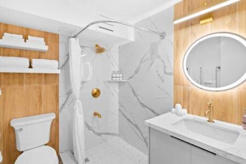 La salle de bains est pourvue de toilettes, d'un lavabo et d'un miroir. dans l'établissement NEWLY Remodeled Upscale Design Central Waikiki, à Honolulu