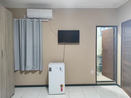 um quarto com um frigorífico e uma televisão na parede em Pousada Bem-te-vi em Aracaju