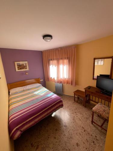um quarto com uma cama e uma televisão em Casa Martina em Guadalaviar