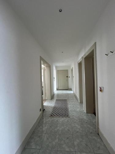 un couloir vide avec des murs blancs et du carrelage dans l'établissement Logement spacieux, à Mulhouse