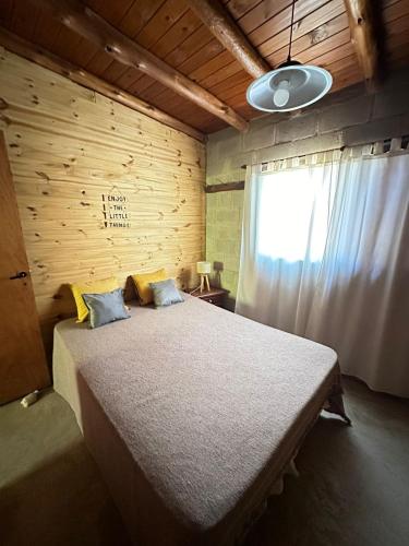 a bedroom with a large bed with a wooden wall at Cabañas del Amanecer in Tanti