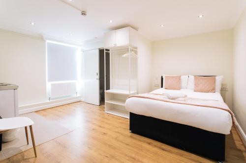 a bedroom with a large bed with white walls and wood floors at The Chapter - Hyde Park Hotel in London