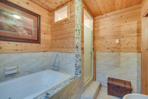 ein Badezimmer mit einer Badewanne an einer Holzwand in der Unterkunft Barnum Cabin on 30 Acres with Soo Line Trail Access! 