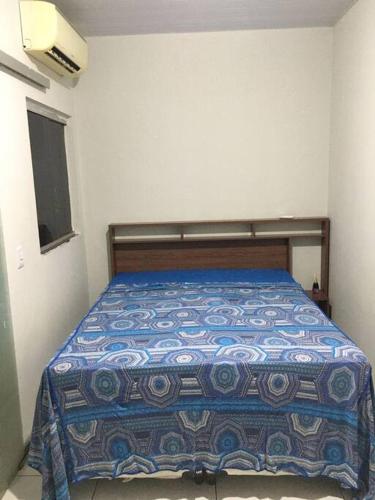 a bedroom with a bed with a blue comforter at Stúdio Cozy in Palmas