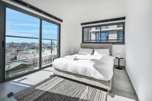 una camera da letto con un letto bianco e ampie finestre di Glamorous 3BR Penthouse near Rothschild Boulevard a Tel Aviv