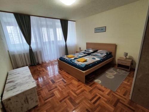 a bedroom with a bed and a wooden floor at MI Apartment in Subotica
