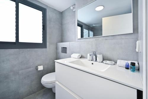 La salle de bains est pourvue d'un lavabo blanc et de toilettes. dans l'établissement Glamorous 3BR Penthouse near Rothschild Boulevard, à Tel Aviv