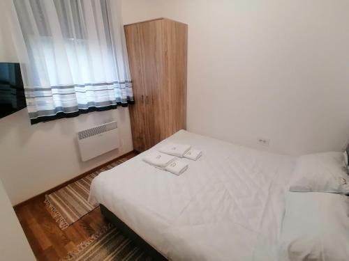 1 dormitorio con 1 cama con sábanas blancas y ventana en Milnik apartman, en Zlatibor