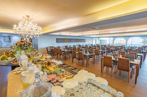a large banquet hall with tables and chairs and a chandelier at Hotel Village Premium Campina Grande in Campina Grande
