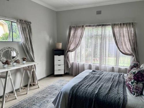 um quarto com uma cama, uma secretária e uma janela em Lilibeth guesthouse em Parys