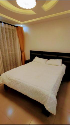 a bedroom with a large bed with white sheets at Dora's Apartment in Kampala