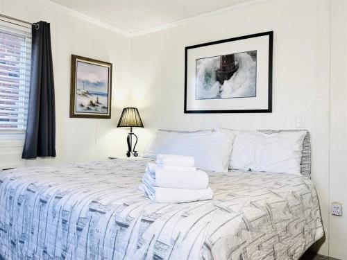 a white bedroom with a bed with towels on it at Stunning 2BR/2BA Bayfront Retreat in Ocean City