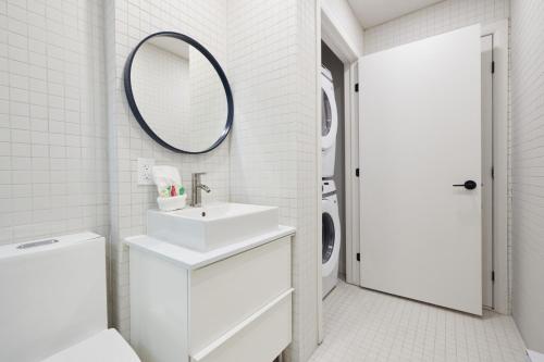 a white bathroom with a sink and a mirror at Chic 2 Bedroom apartment in Le Plateau by Denstays in Montréal
