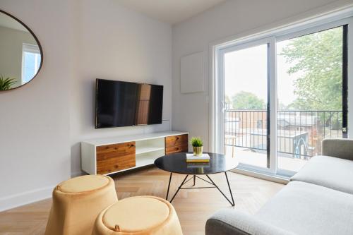a living room with a tv and a couch and a table at New and Cozy 3 bedroom in Le Plateau by Denstays in Montréal
