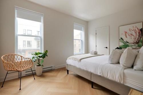 a bedroom with a bed and a chair and windows at Spacious 2 bedroom apartment in Le Plateau by Denstays in Montréal