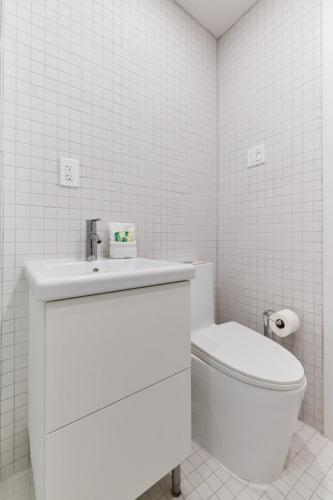a white bathroom with a toilet and a sink at Spacious 2 bedroom apartment in Le Plateau by Denstays in Montréal